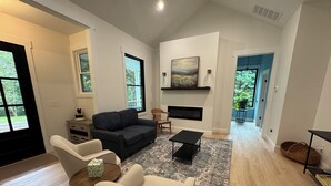 Un salón amplio con chimenea, un ventanal y vistas al exterior.