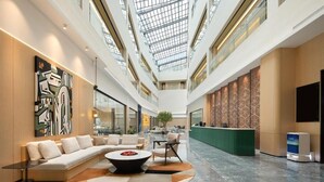 A spacious lobby with a high ceiling, a central seating area, and a reception desk. - Guangzhou Chimelong Expo Center Jincheng Hotel (Guangzhou)