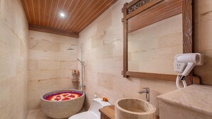 A modern bathroom with a stone sink, a toilet, and a shower. - KIRANI HOUSE (Batubulan)