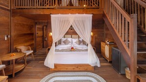 A wooden bedroom with a four-poster bed, a balcony, and a staircase. - KIRANI HOUSE (Batubulan)