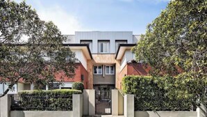 Ein modernes Gebäude mit einer symmetrischen Fassade, einem zentralen Eingang und einem befestigten Einfahrtsweg.