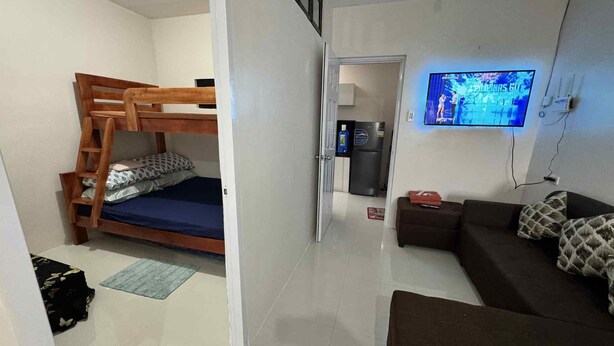 Ein Zimmer mit Etagenbett, einer Schlafcouch, einem Fernseher und einem Kühlschrank.