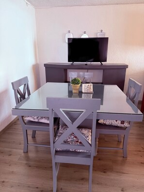 A dining area with a glass-top table, grey upholstered chairs, a small potted plant, and a flat-screen TV mounted above the table. - Spacious, comfortable and centrally located house. (Ciudad de Apizaco)