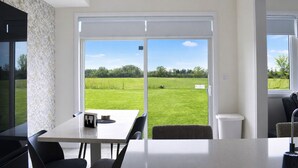 Een moderne keuken met een eethoek, grote schuifdeuren naar een grasveld en uitzicht op het buitengebied.