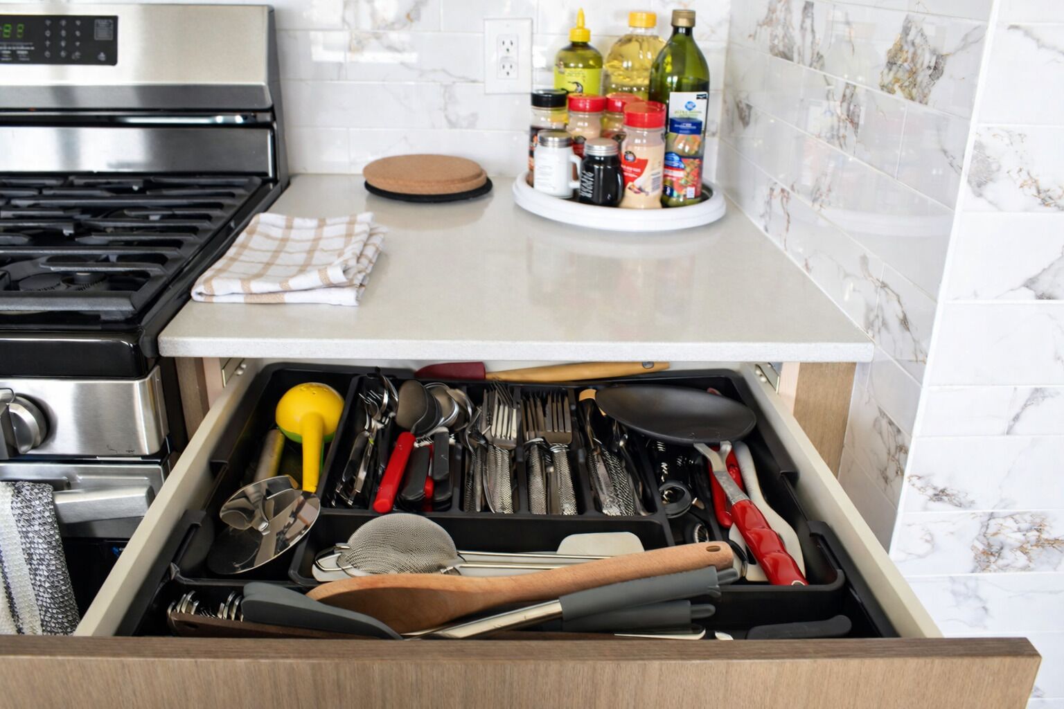 Une cuisine équipée d’une cuisinière, d’un tiroir contenant des ustensiles et d’un porte-épices.