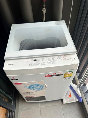 A white Toshiba washing machine with a control panel, a water inlet, and a drain hose. - City View Condo - Pool, Gym – BTS Talat Phlu (Bang Chak, Phra Khanong)