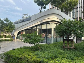 A modern building with a curved facade, a sign reading 'LAWSON 100,' and a glass storefront. - City View Condo - Pool, Gym – BTS Talat Phlu (Bang Chak, Phra Khanong)