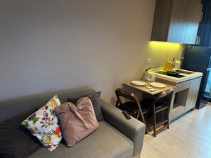 Ein kompakter Wohnbereich mit Sofa, Esstisch und Küchenzeile.
