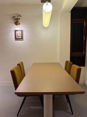 Ein Konferenzraum mit einem langen Tisch, vier Stühlen, einer Wandleuchte und einem gerahmten Bild.