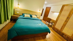 Quarto com cama, mesas de cabeceira, escrivaninha e guarda-roupa.