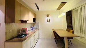 Cozinha moderna com ilha central, mesa de jantar com cadeiras e luminária pendente.