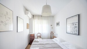 Ein Schlafzimmer mit einem großen Bett, einem Schreibtisch, einem Stuhl, einer Hängelampe und zwei gerahmten Bildern an den Wänden.