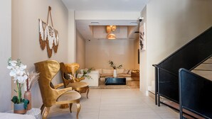 Ein modernes Wohnzimmer mit einer Couch, zwei goldenen Sesseln, einem Couchtisch und einer Treppe.