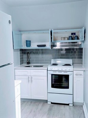 A kitchen with white cabinets, a stove, and a sink. - Top-Rated 1BR | EWR 10 Min + NYC Train | Sleeps 4 (Newark)