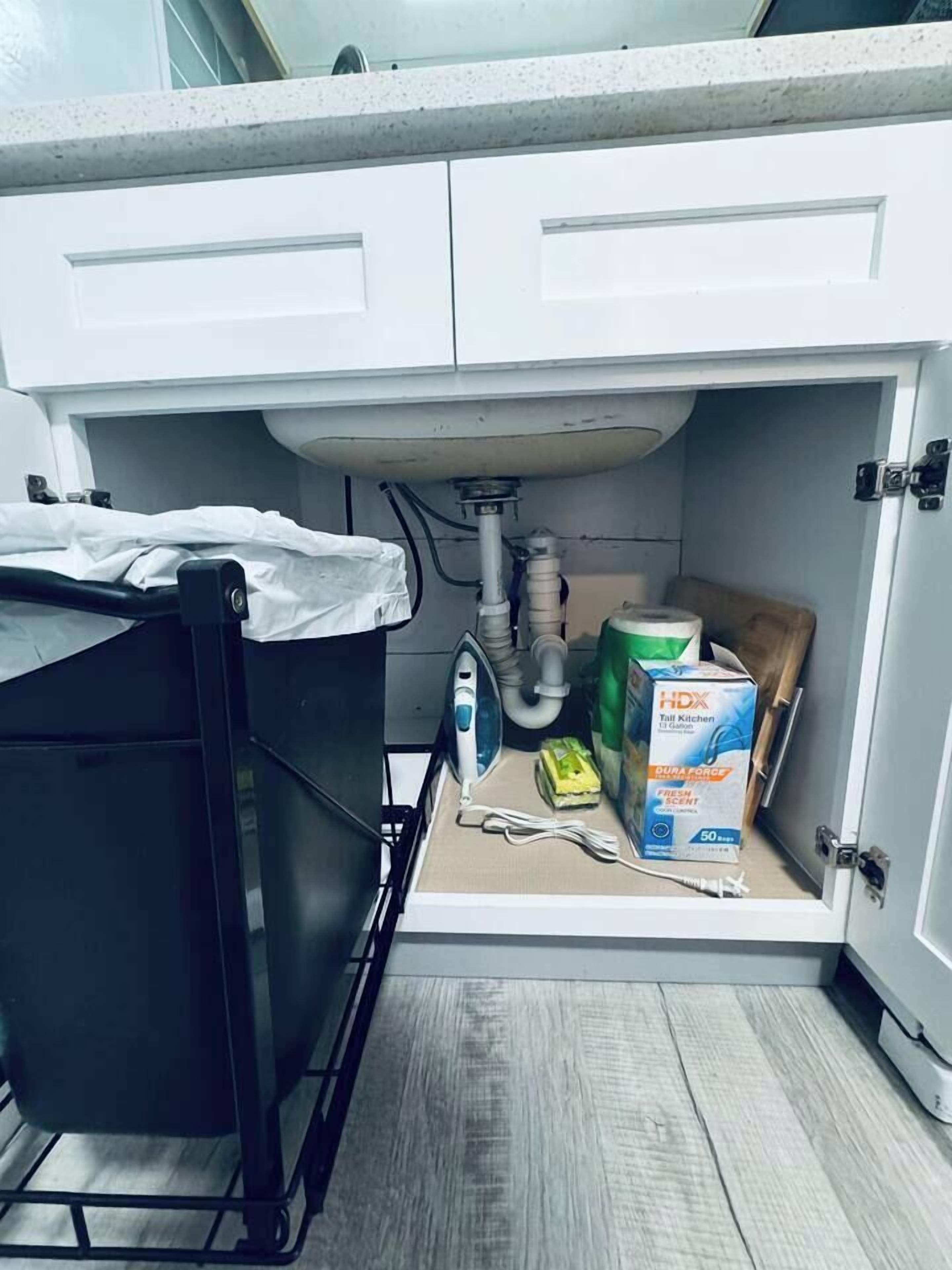Eine Küche mit einer weißen Arbeitsplatte, einem schwarzen Ablagerungselement und einer Packung HDX Toilettenpapier.