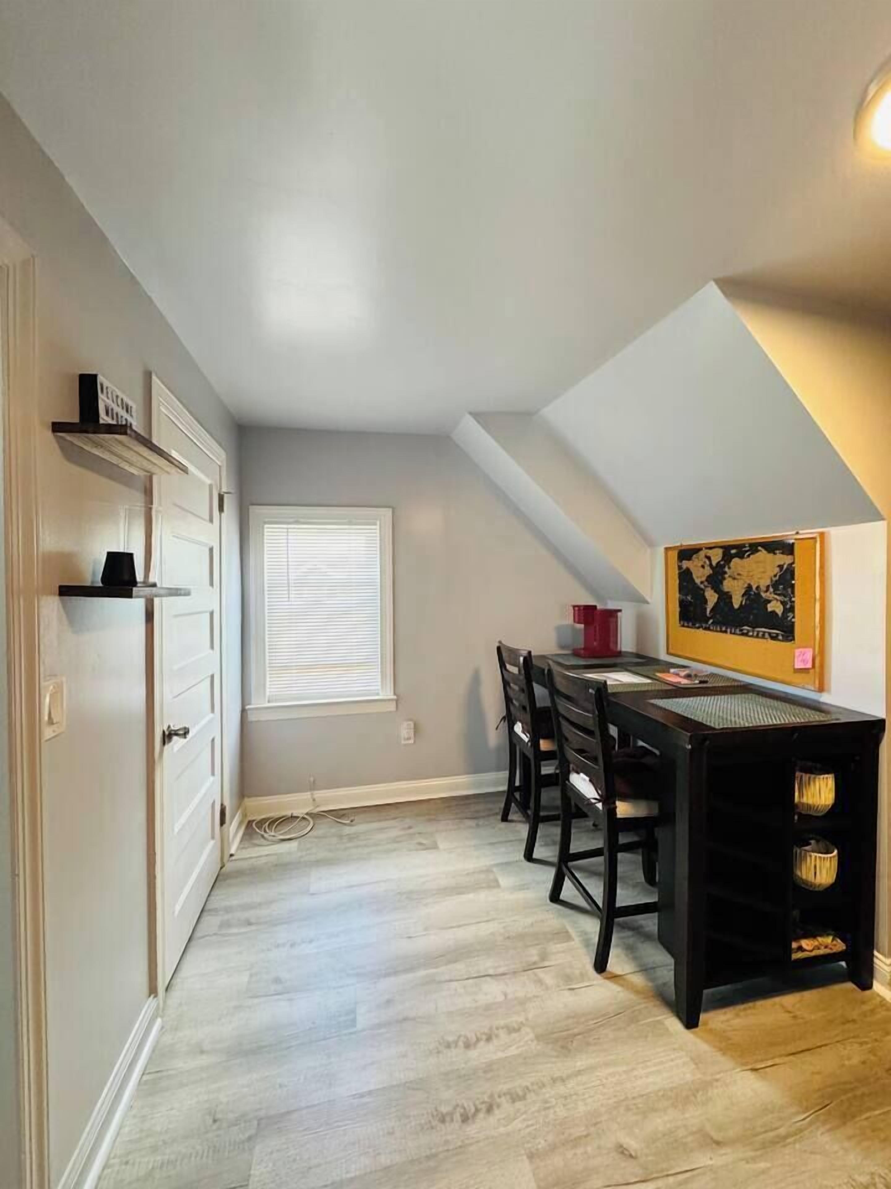 A dining area with a table and chairs, a window with blinds, and a wall-mounted map.