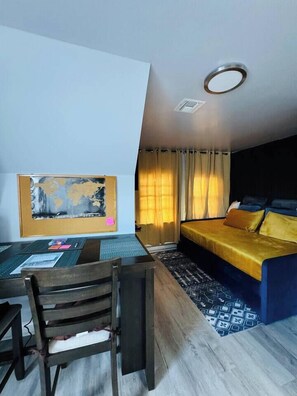 A room with a bed, a desk, chairs, a world map on the wall, and a window with curtains. - Top-Rated 1BR | EWR 10 Min + NYC Train | Sleeps 4 (Newark)