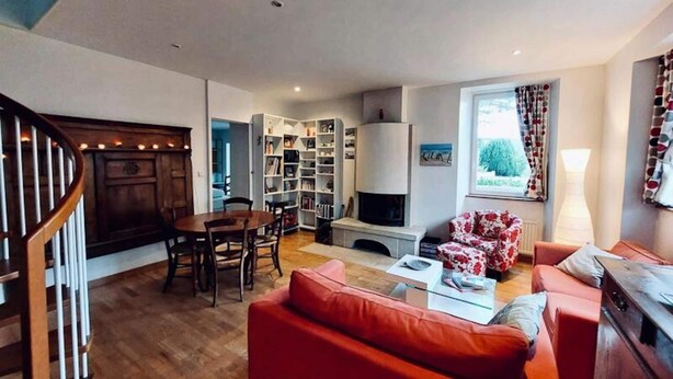 A cozy living room with a fireplace, a dining area, and a staircase. - House in Tregastel Near Pink Granite Coast (Tregastel)