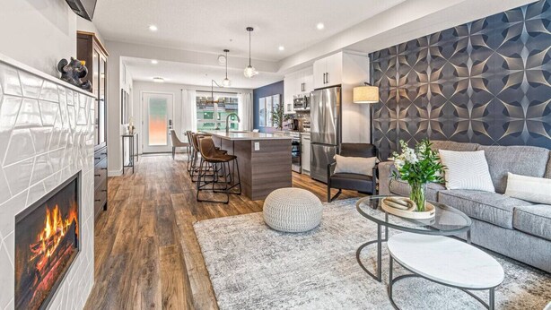 A modern kitchen with a central island, a dining area with chairs, a sofa, and a fireplace. - Classic Modern 4BR Nearby DT with Hot tub & Pool (Canmore)