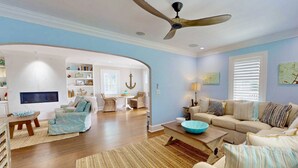 Un salon spacieux doté d’un ventilateur de plafond, d’un grand canapé, d’une table basse et d’un téléviseur.