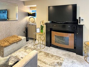 A modern living room with a fireplace, a sofa, a television, and a small table with a plant. - Oasis Boutique - UK51036 (Bowness-on-Windermere)