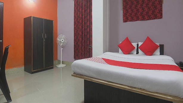 A bedroom with a bed, a wardrobe, a standing fan, and a red curtain. - Hotel O by OYO Am Bed And Breakfast (Shillong)