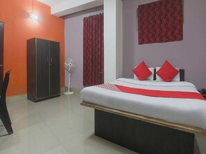 Quarto com cama, guarda-roupa, ventoinha e cortina vermelha.