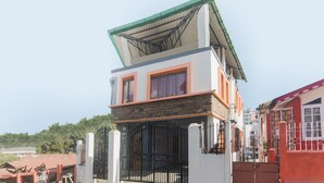 A two-story building with a flat roof and a gated entrance. - Hotel O by OYO Am Bed And Breakfast (Shillong)