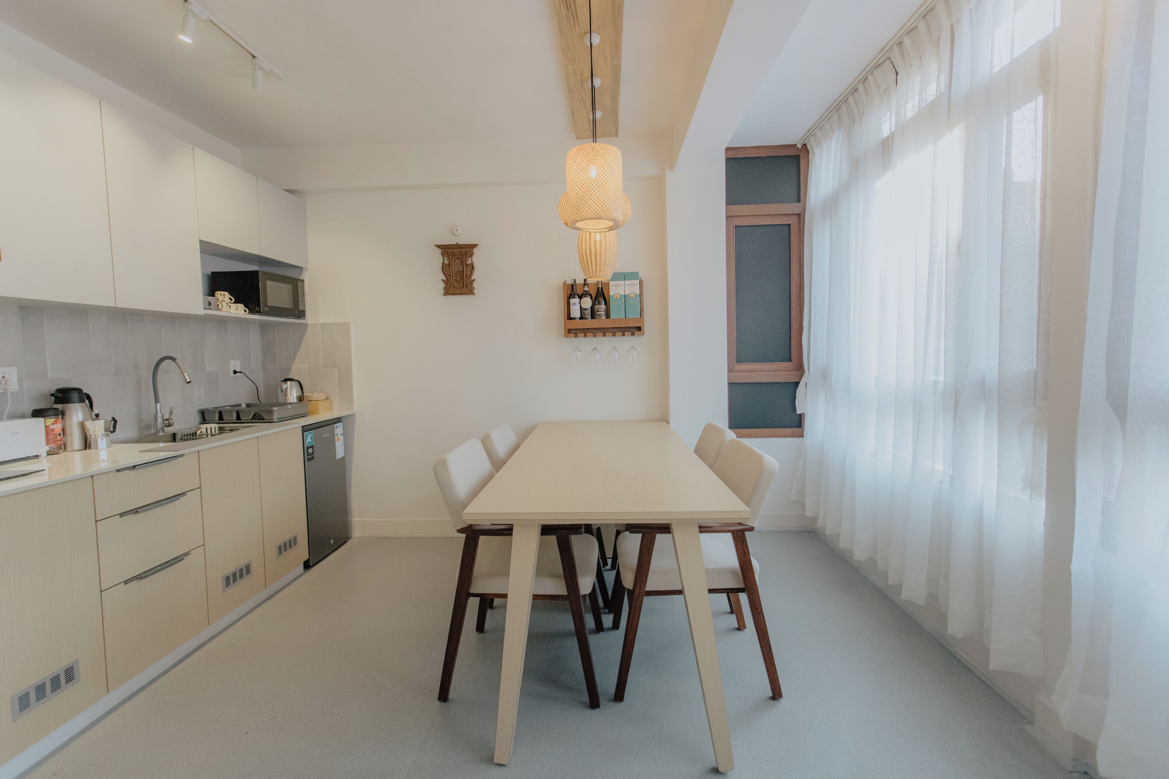 Une cuisine moderne avec une table à manger, des meubles blancs et un luminaire suspendu.
