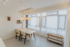 Un comedor moderno con una mesa blanca, sillas y un banco de madera.