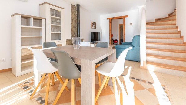 A modern living room with a dining area, a staircase, and a stone fireplace. - Villa Sheike V3 com Piscina Privada (Tavira)