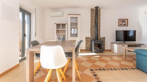 A modern living room with a dining table, chairs, a TV, and a fireplace. - Villa Sheike V3 com Piscina Privada (Tavira)
