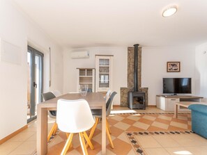 A modern living room with a dining table, chairs, a TV, and a fireplace. - Villa Sheike V3 com Piscina Privada (Tavira)