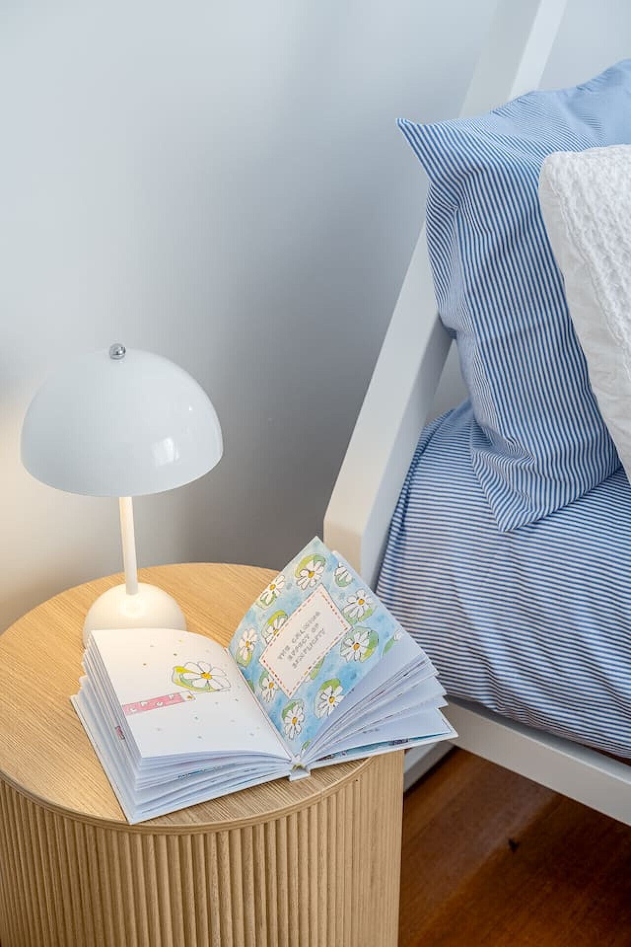 A bedside table with a lamp and a stack of books.