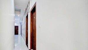 Un pasillo con paredes blancas, suelo de mármol y puertas de madera.