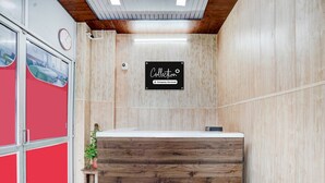 Mostrador de recepción con detalles de madera, un reloj y un cartel que indica que el servicio está disponible.