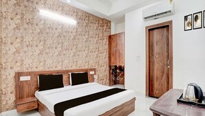 Una habitación de hotel con una cama de madera, una mesita de noche pequeña, un armario y una mesa de centro.