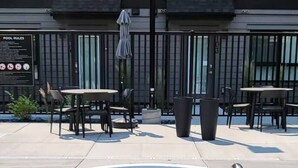 A small, rectangular pool with a metal ladder, surrounded by outdoor seating and a building with balconies in the background. - Chick & Cozy Haven near Banff with Hot tub & Pool (Canmore)