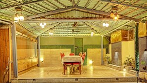 Un espace de restauration intérieur avec un patio couvert, une table dressée pour deux personnes et un mur végétal agrémenté d’une porte.