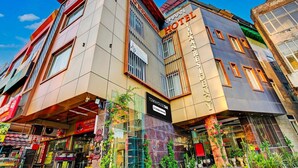 Un hôtel moderne, reconnaissable à son grand panneau indiquant « HÔTEL », à son panneau « CAFÉ CHAUD » et à son panneau « TOWNHOUSE OAK ».