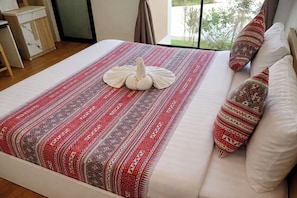 A neatly made bed with a patterned blanket and a swan-shaped pillow.