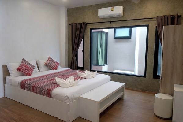 Un dormitorio moderno con una cama, mesitas de noche, una ventana y un equipo de aire acondicionado.