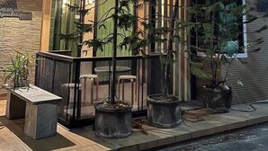 Un bâtiment moderne doté d’un balcon, de plantes en pot et d’un banc en pierre.