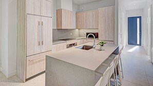 Una cocina moderna con armarios de madera clara, una isla central con un fregadero y un horno empotrado.