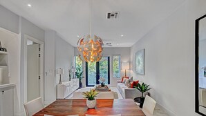 Un comedor moderno con una mesa de madera, sillas blancas y una lámpara colgante original.