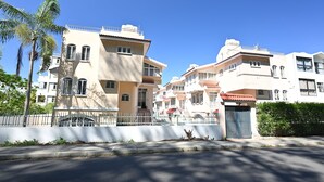 Un immeuble résidentiel à plusieurs étages, doté de balcons et d’une entrée sécurisée par un portail.