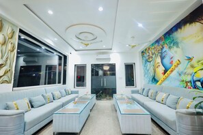 A modern hotel lobby with a large window, a mural, and a seating area with sofas and tables. - BUDDHA DHAM (Vrindavan)
