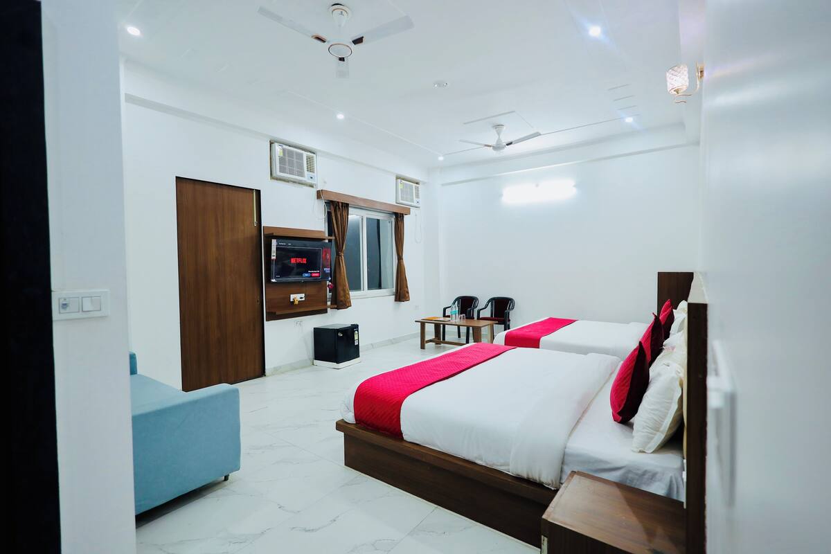 Une chambre d’hôtel avec deux lits, une télévision, un bureau et une chaise bleue.