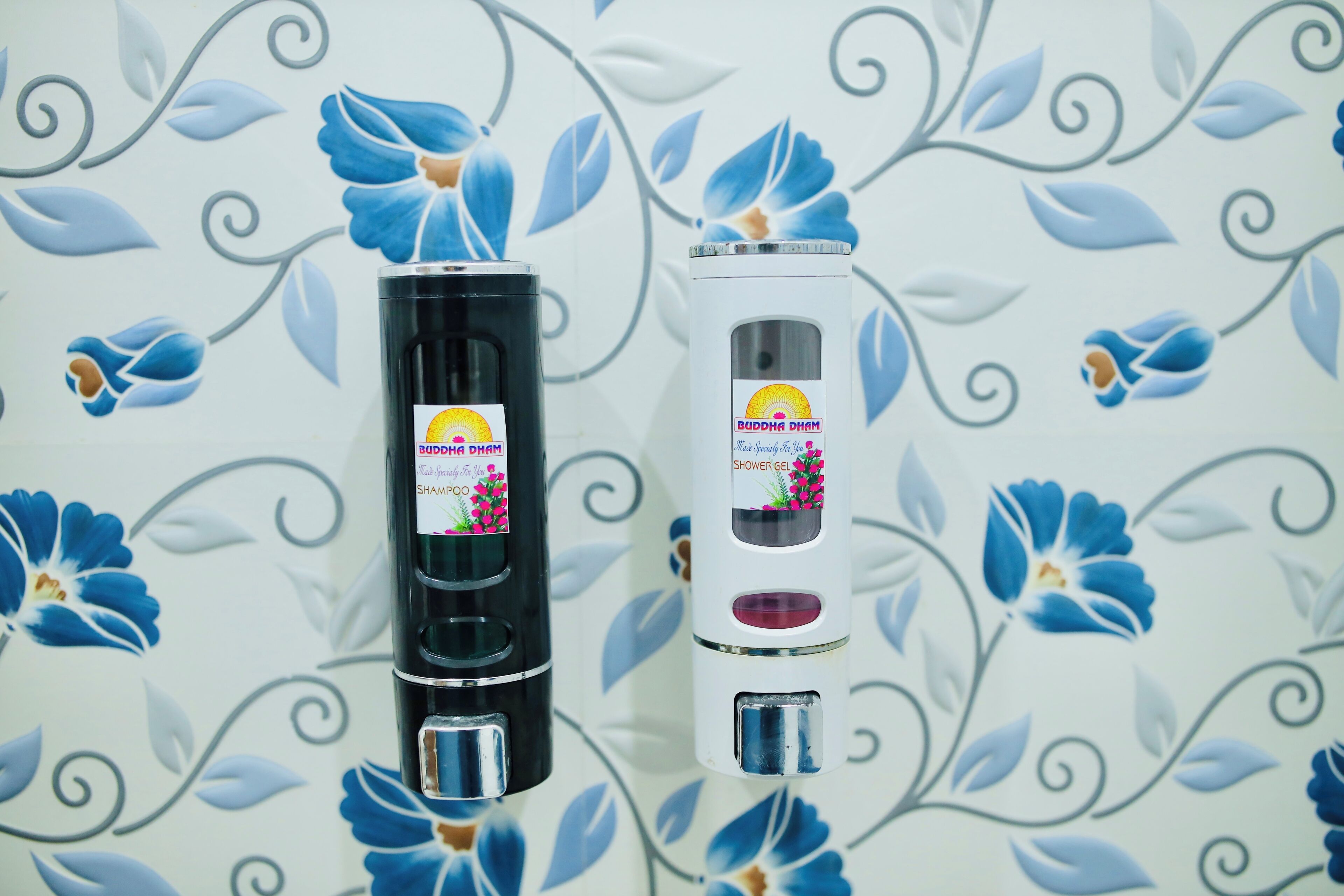 Two bottles of shower gel against a floral wallpaper background.