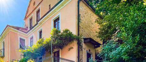 Un immeuble de deux étages doté d’un balcon et d’une façade en pierre.